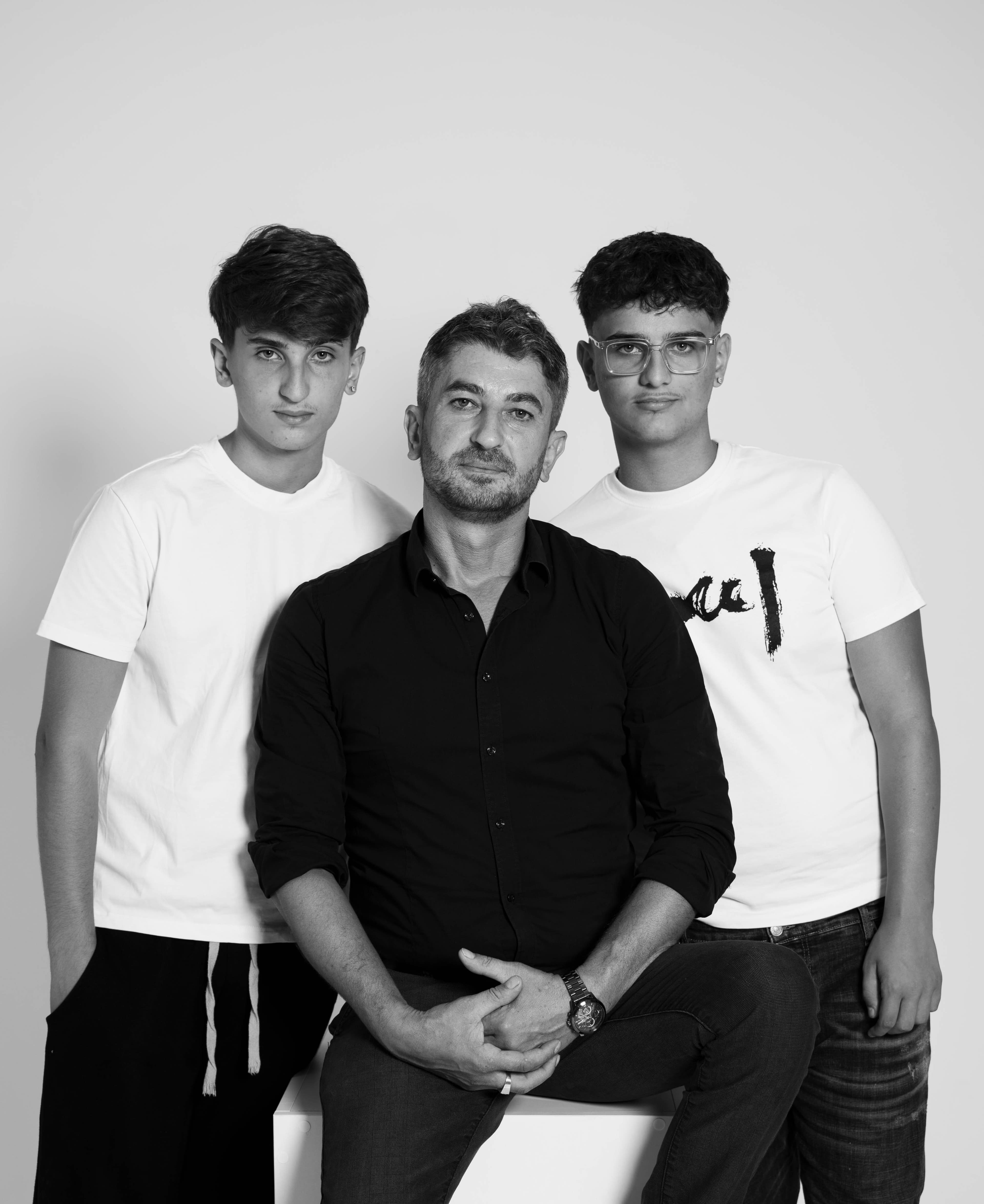 Father seated between his two teenage sons in a black-and-white studio portrait