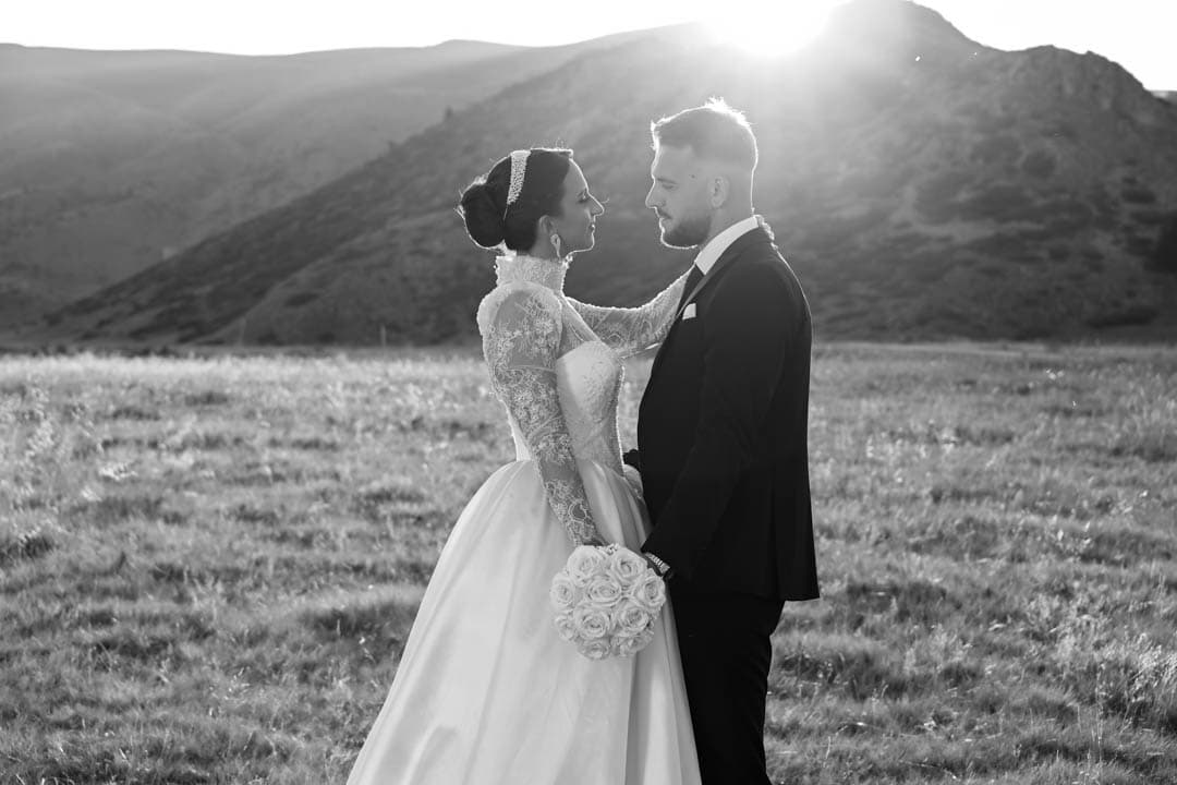 Bride and groom facing each other in a sunlit mountain meadow